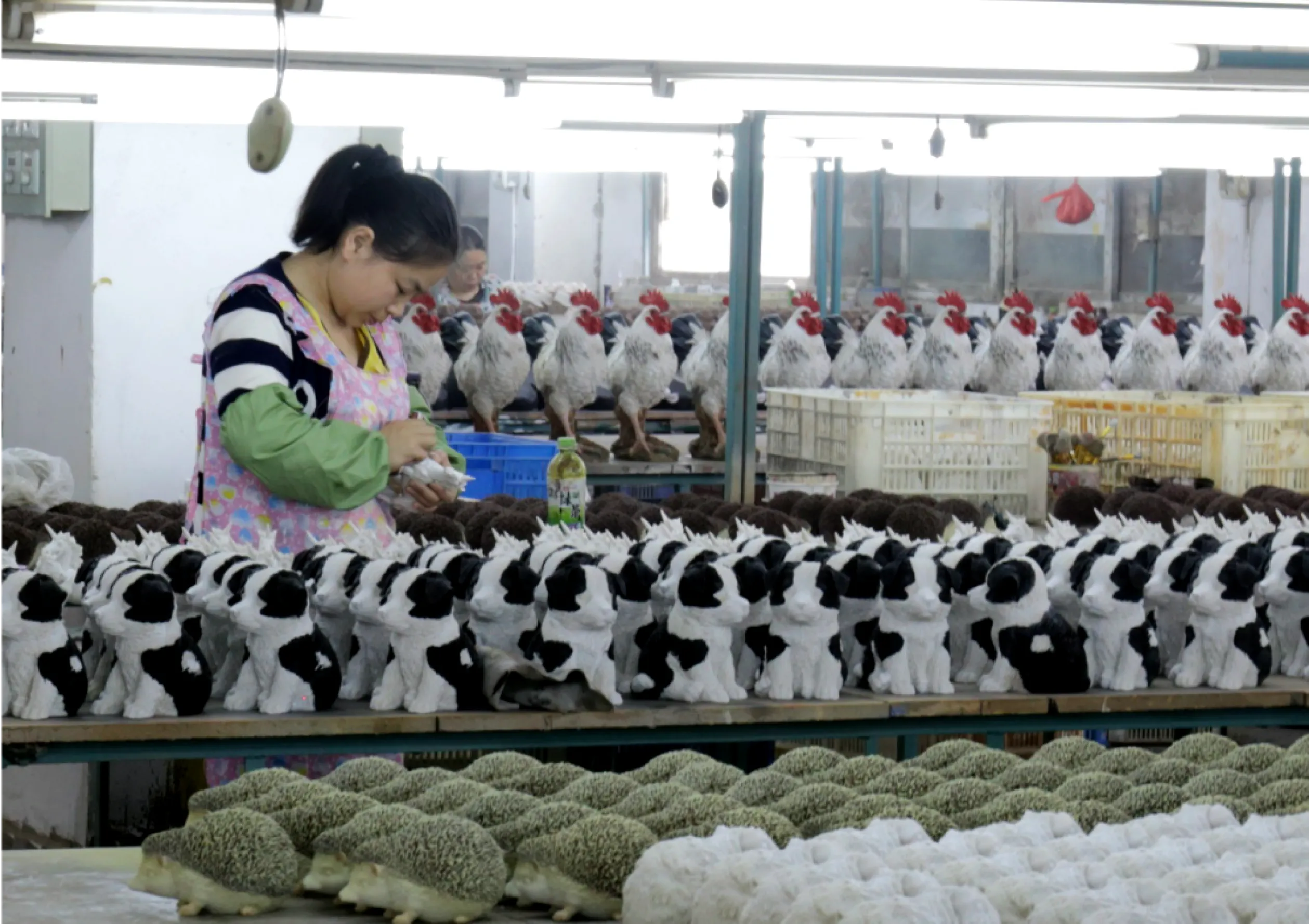 Woman works on a table filled with figurines of black and white cats